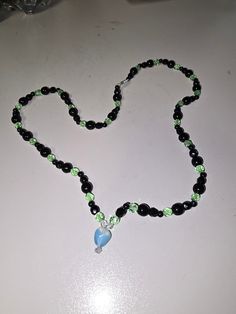 A beautiful one of a kind black and green hand beaded glass necklace. Pair it with the perfect outfit or gift it to a loved one! Black Glass Beaded Necklaces With Colorful Beads, Black Glass Beaded Necklace With Colorful Beads, Black Glass Beaded Necklaces With Beaded Chain, Black Glass Beaded Necklace With Beaded Chain, Black Glass Round Bead Jewelry, Black Glass Round Beads Jewelry, Black Glass Beaded Jewelry, Black Beaded Glass Necklaces, Black Beaded Glass Necklace