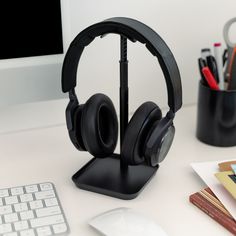 a desk with a keyboard, mouse and headphones sitting on it's stand