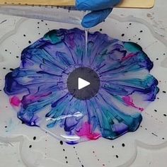 a person in blue gloves is painting a flower