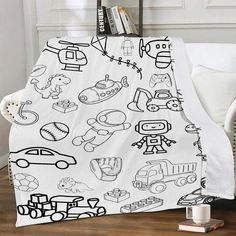 a blanket with black and white drawings on it sitting in front of a chair next to a bookshelf