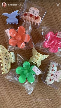 several different types of hair clips in plastic bags on a wooden table with tags attached to them