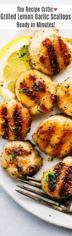 grilled lemon garlic scallops on a white plate with a fork and lemon wedges