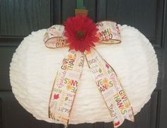 a wreath made out of yarn with a red flower and ribbon attached to the top