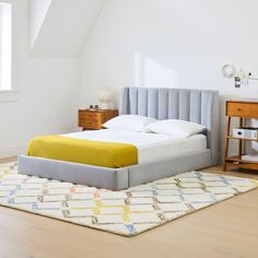 a bed sitting on top of a wooden floor next to a dresser and window in a bedroom