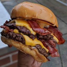 a bacon cheeseburger is being held up to the camera