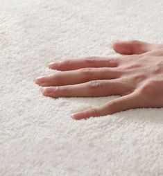 a person's hand resting on a white rug