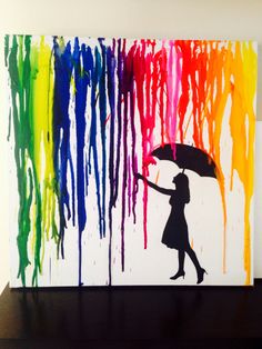 a woman holding an umbrella in front of a rainbow painting on a white wall with black paint dripping all over it