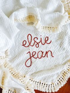 an embroidered dishcloth with the word elsie jean written on it, sitting on a wooden surface