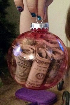 someone is holding up a christmas ornament with money in the shape of a ball