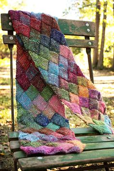 a multicolored blanket sitting on top of a wooden bench