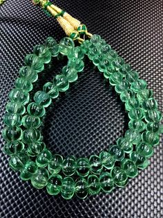 a green beaded necklace on a black surface