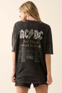 Distressed, mineral washed graphic t-shirt. Torn and distressed detailing at neckline, cuffs, and hem. Vintage-style back print with AC/DC logo and "For Those About to Rock" 1982 tour dates. Thunderbolt chest print. Round neckline. Short sleeves. Drop shoulder. Oversized fit. 100% Cotton. Imported top designed and printed in LA. Officially licensed AC/DC merchandise. Model wears size S. Stonewashed Band Merch T-shirt For Streetwear, Trendy Acid Wash T-shirt For Concert, Grunge Acid Wash Distressed T-shirt, Distressed Acid Wash Band Merch T-shirt, Edgy Faded Distressed T-shirt, Alternative Style Black Washed Tops, Stonewashed Band Merch T-shirt With Crew Neck, Band Merch Stonewashed Crew Neck T-shirt, Oversized Distressed Band Merch T-shirt