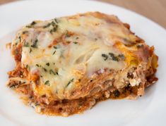 a white plate topped with lasagna casserole covered in cheese and herbs