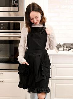 a woman standing in a kitchen wearing an apron