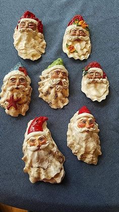 twelve santa claus ornaments are arranged on a blue tablecloth with a wooden chair in the background