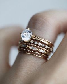 a close up of a person's hand with two rings on their fingers and one has a diamond in the middle