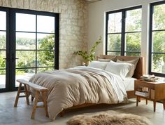 a bedroom with stone walls and large windows