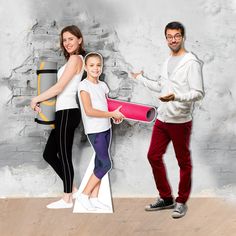 a man and two women standing in front of a brick wall holding a pink object