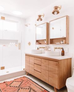 a bathroom with two sinks, mirrors and a rug on the floor in front of it