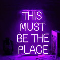 a neon sign that says, this must be the place in front of a computer