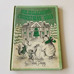 an old children's christmas book with two mice in front of a house and trees