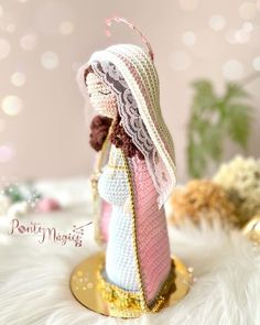 a crocheted angel figurine with a pink and white scarf on it's head