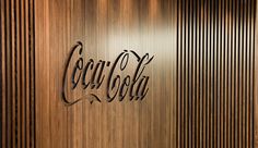 the coca - cola logo is displayed on a wooden wall in an office building with wood slats