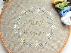 a cross - stitch hoop with the words happy easter on it next to some yarn and scissors