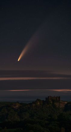 an object is seen in the sky over a hill at night with stars above it