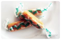 two pieces of candy wrapped in plastic sitting on a white plate with green and orange strips