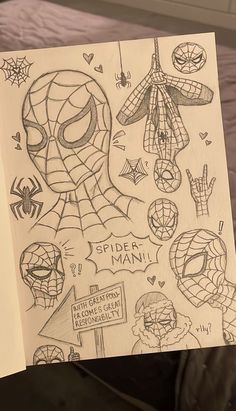 a person holding up a drawing with spider man and other drawings on it in front of a bed