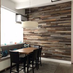 a dining room table and chairs in front of a wooden wall with wood planks on it