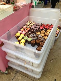 several plastic containers filled with cupcakes on top of a table