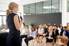 a woman standing in front of a crowd holding a microphone