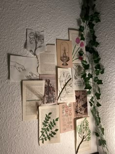 a bunch of papers are hanging on the wall next to a plant and some flowers