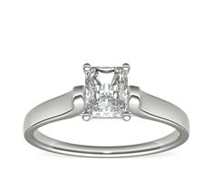 a princess cut diamond engagement ring with two clawed shans on the shoulders and sides