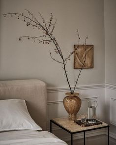 a vase with some flowers on a table in a room that has white walls and flooring