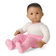 a baby doll sitting on the ground wearing pink and white striped pants, with black hair