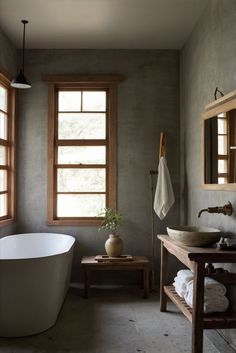 a bath room with a tub a sink and two windows