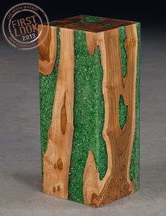 a wooden box with green moss on the outside and wood in the inside, sitting on a gray surface