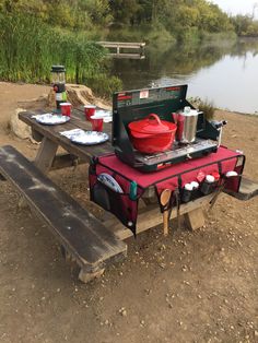 the picnic table is set up by the water with utensils and plates on it