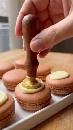 a person is stamping pastries on top of a white tray with other pastries