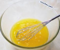 a glass bowl filled with orange juice and whisk