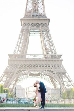 a man and woman kissing in front of the eiffel tower