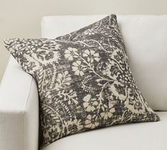 a white couch with a black and white floral pillow on it's backrest