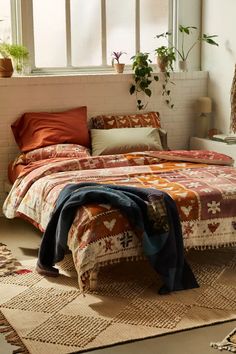 a bed sitting in a bedroom next to a window with potted plants on it