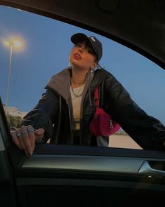 a woman in a car with her hand out the window and looking up into the sky