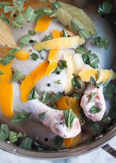 a pan filled with chicken, oranges and herbs