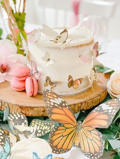 there is a cake with butterflies on it and pink flowers around the cake, along with other decorations