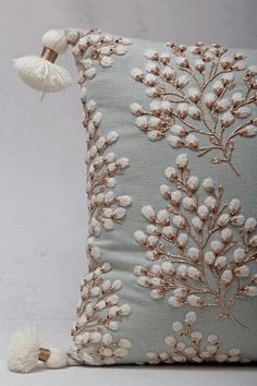 a decorative pillow with white flowers and tassels on the front, along with a pom - pom